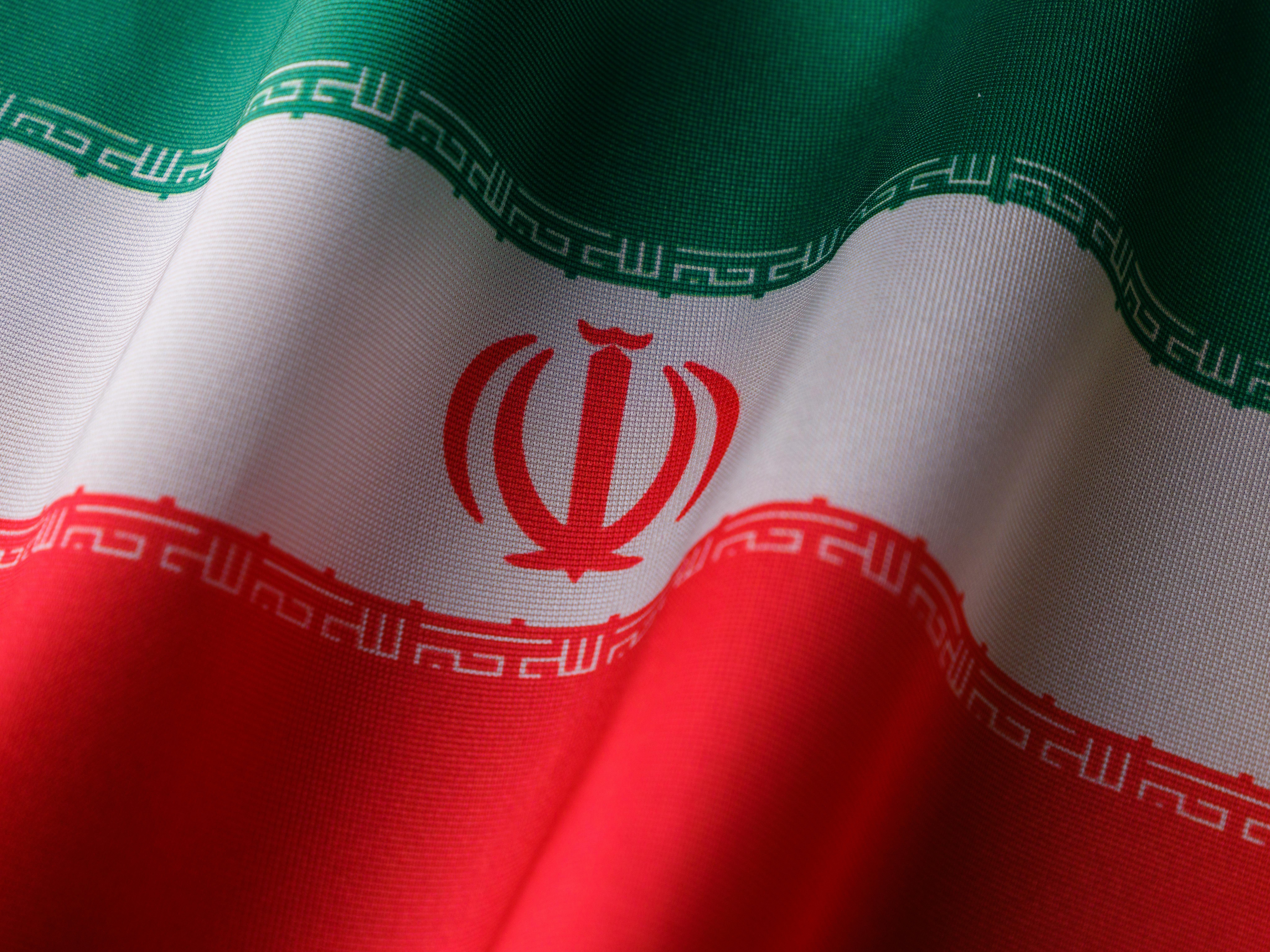 Iranian national flag waving against an urban skyline