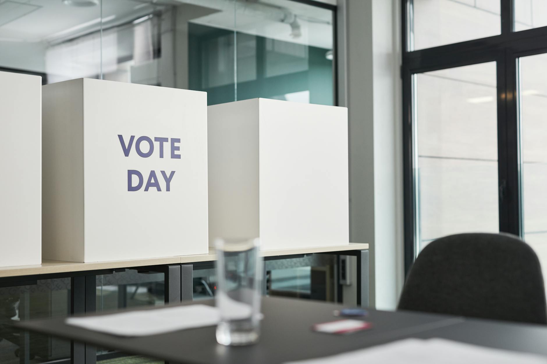 Cardboard ballot boxes labelled Vote Day arranged on a polling-station table