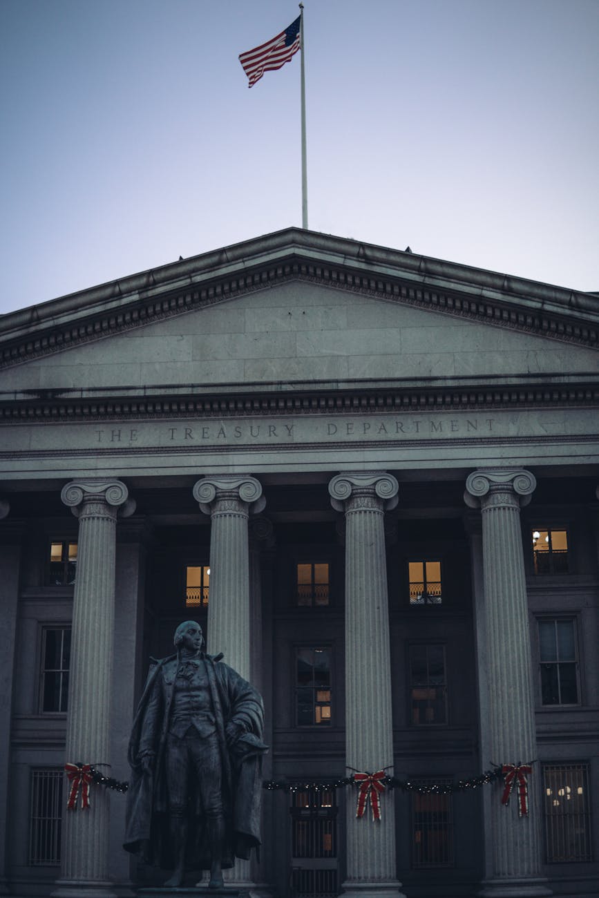 US Treasury Department building facade with columns and American flag at dusk