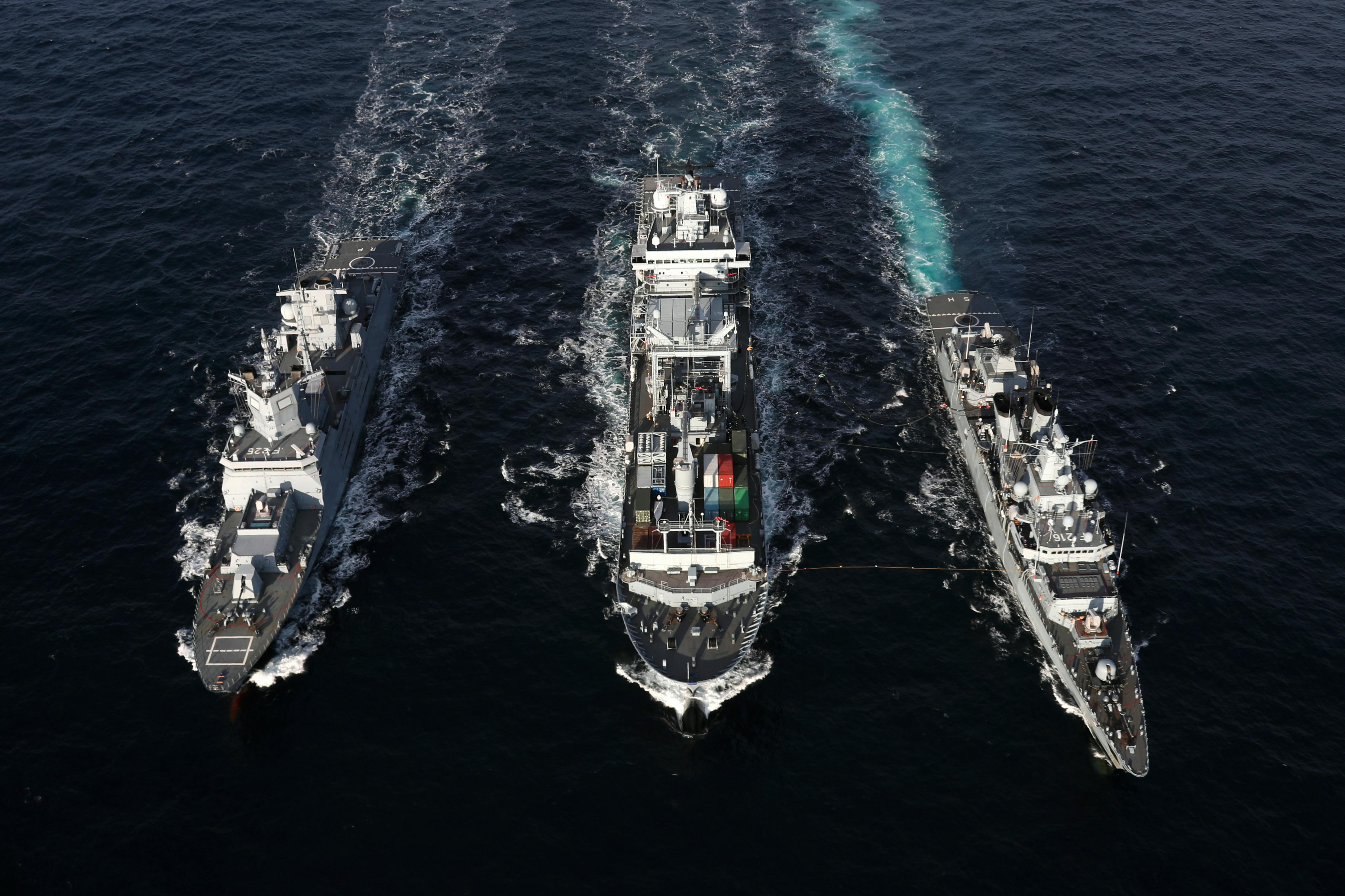 Naval warships sailing in formation on open sea, aerial view