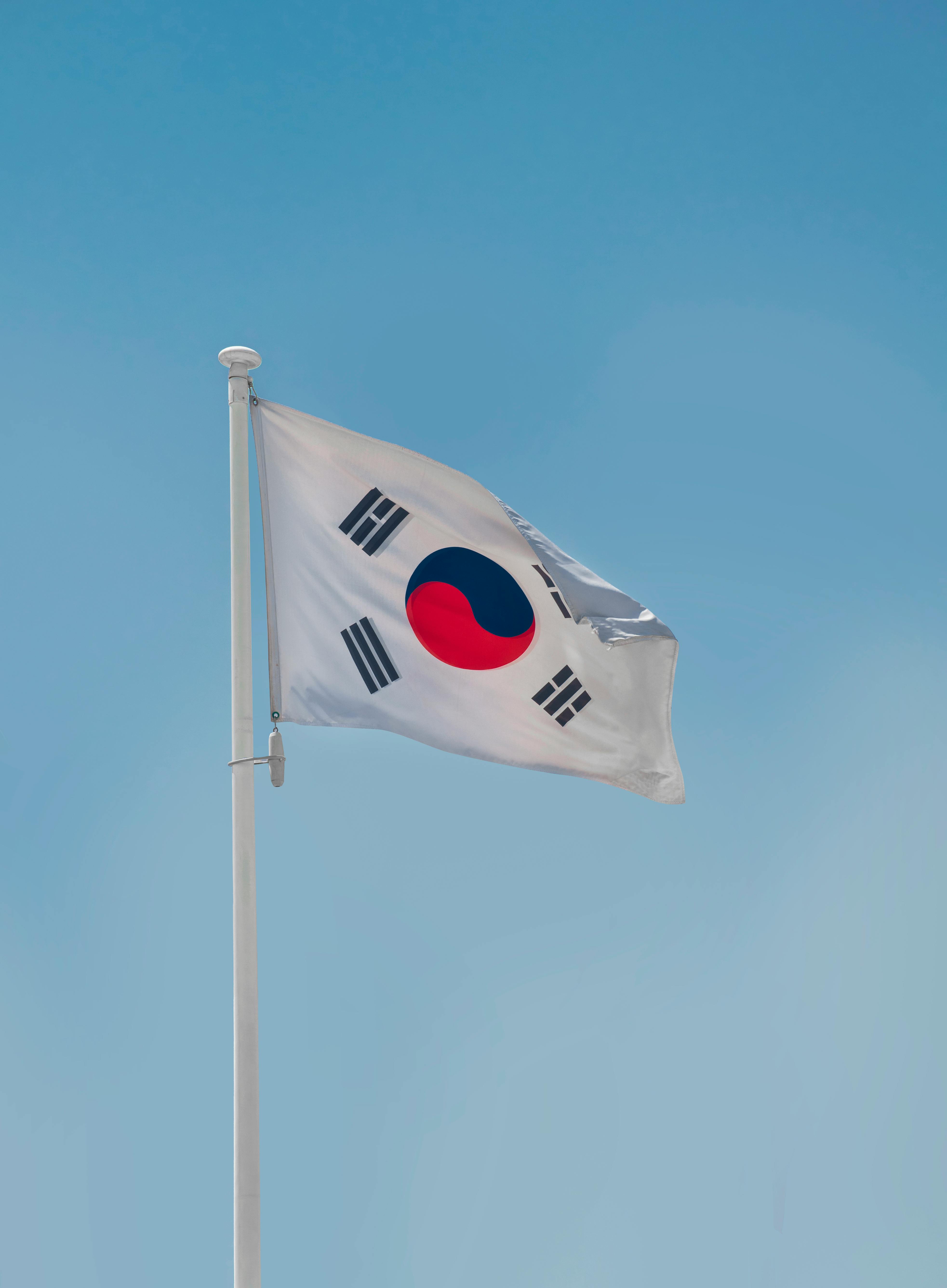 South Korean national flag fluttering on a flagpole against a clear blue sky