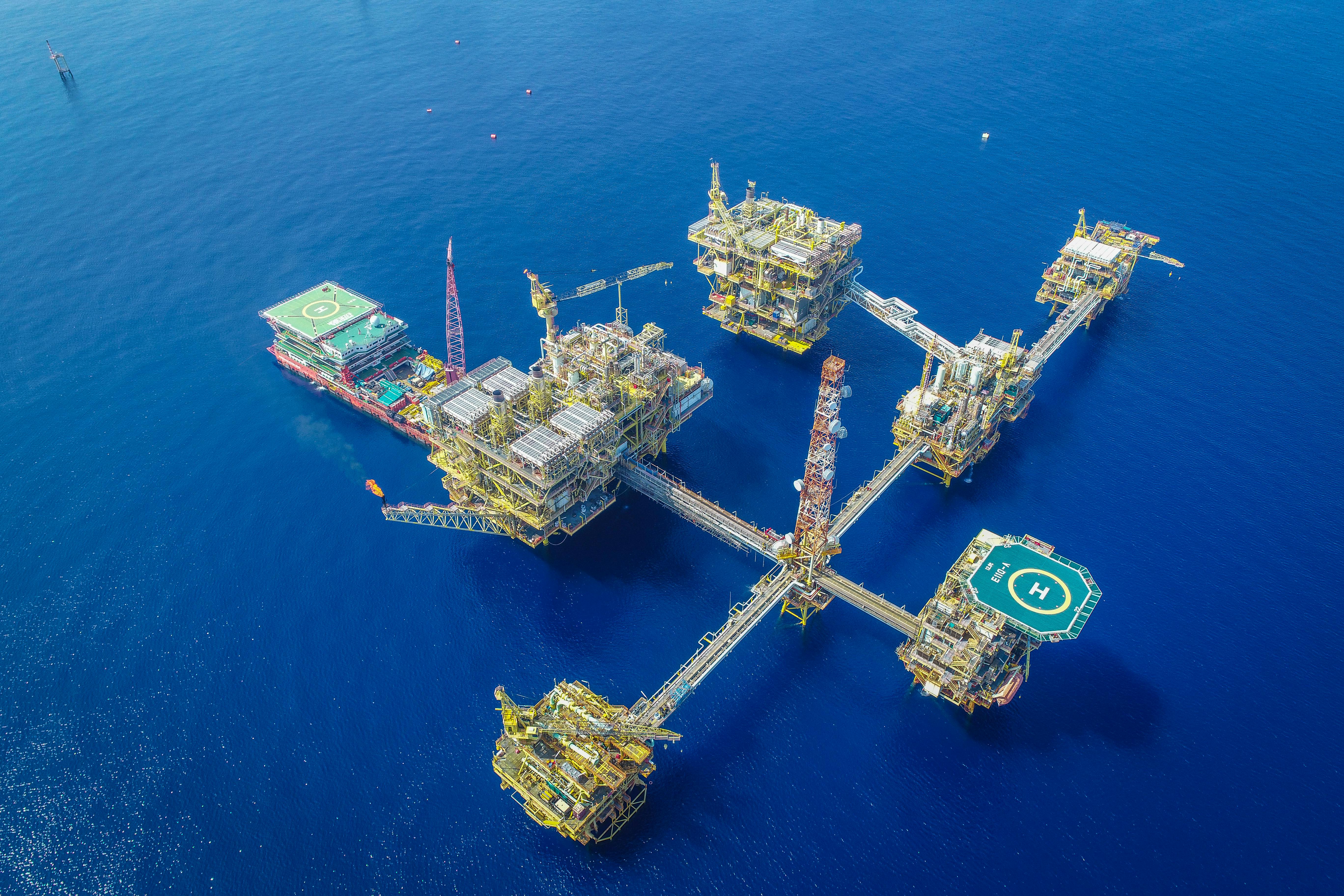 Aerial drone shot of a large offshore oil platform complex in deep blue ocean waters