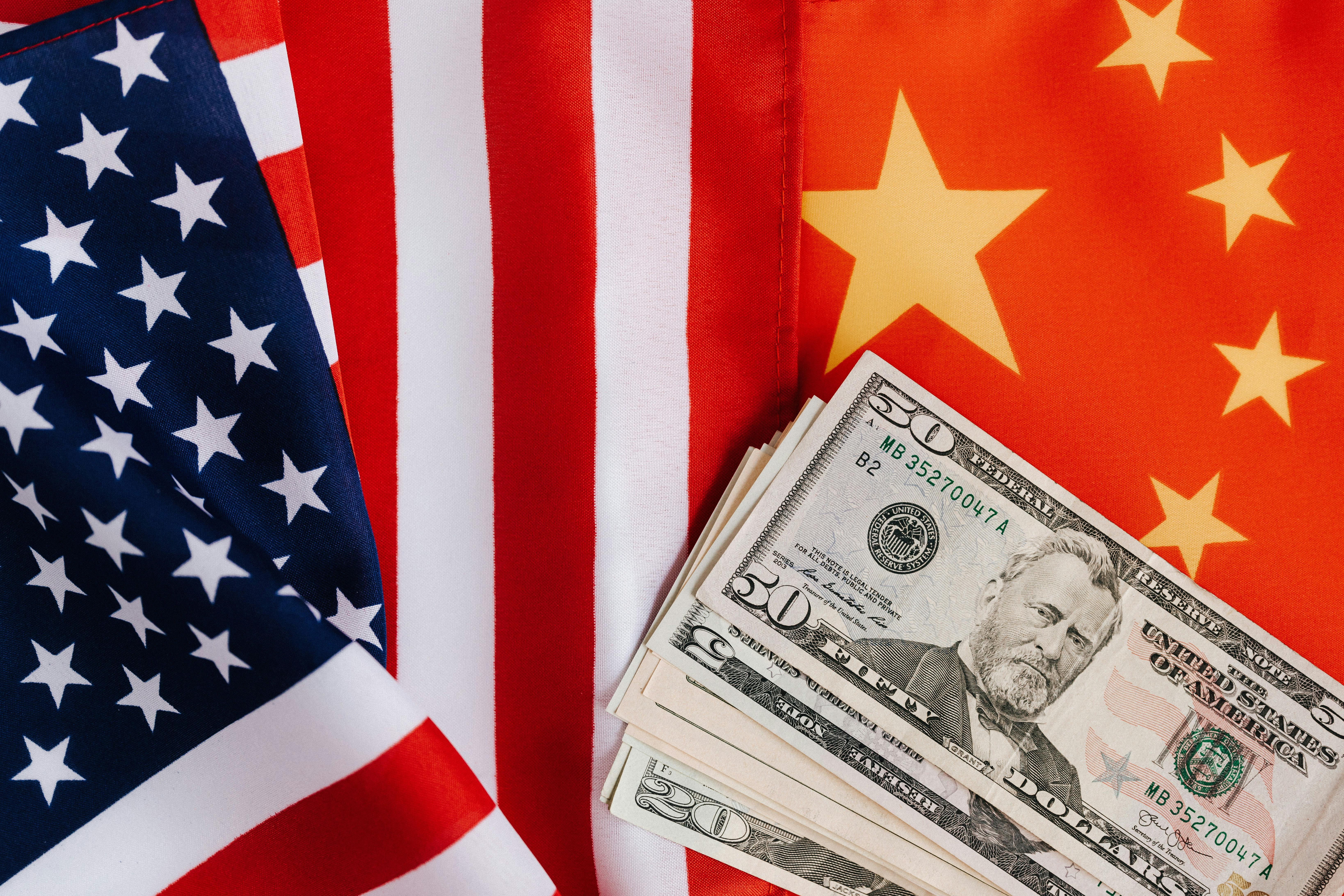 American and Chinese flags with US dollar banknotes illustrating international trade relations