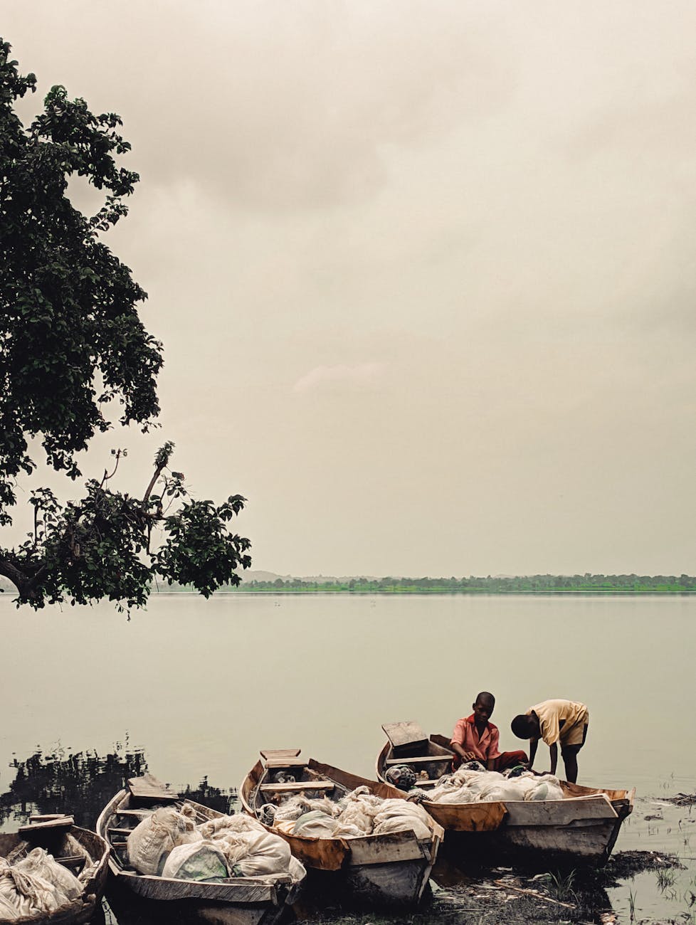 Fishermen working on boats along a tranquil lakeside in Nigeria