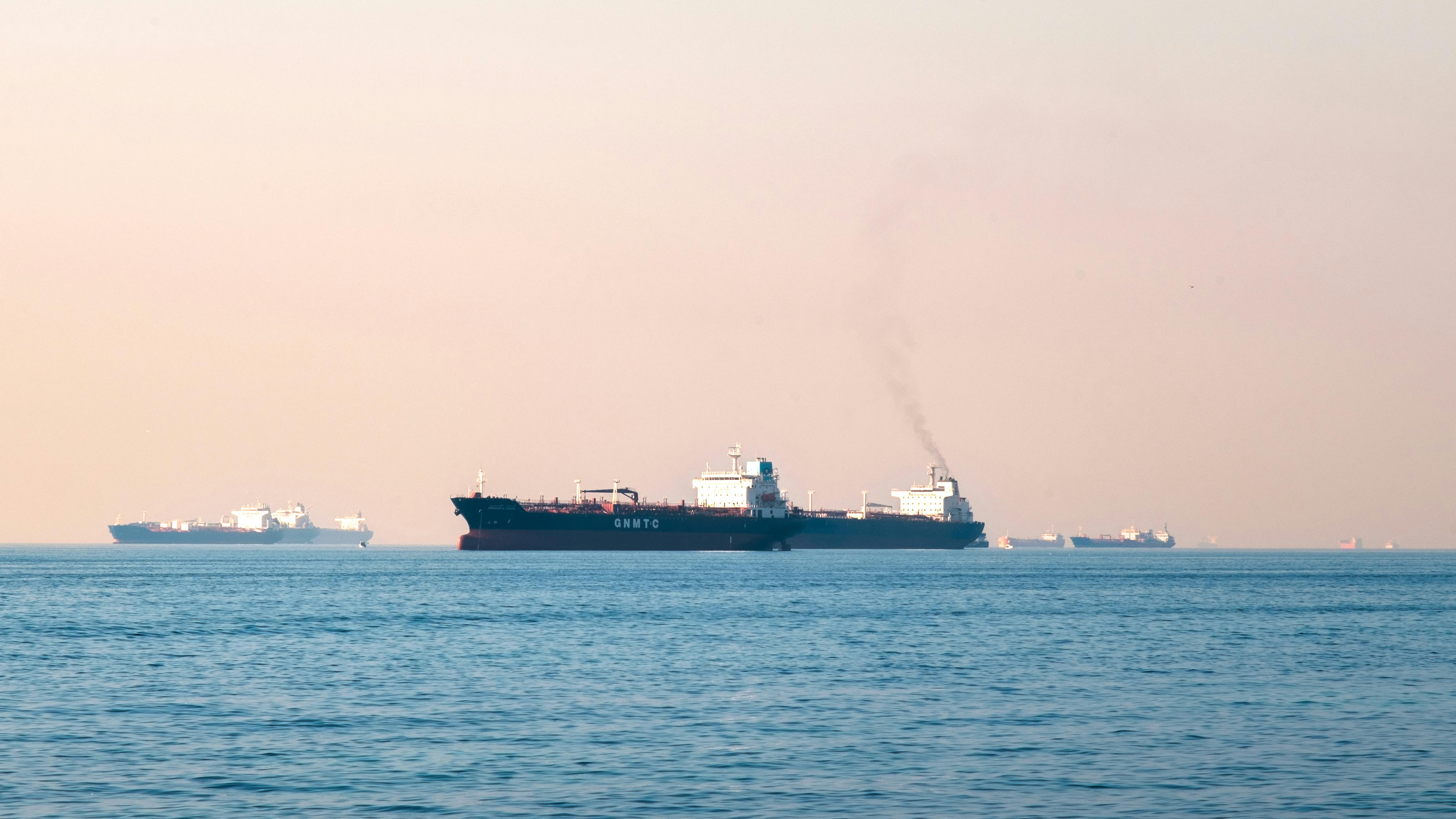 Large industrial tanker ships navigating the open sea under a clear sky, illustrating maritime transportation.