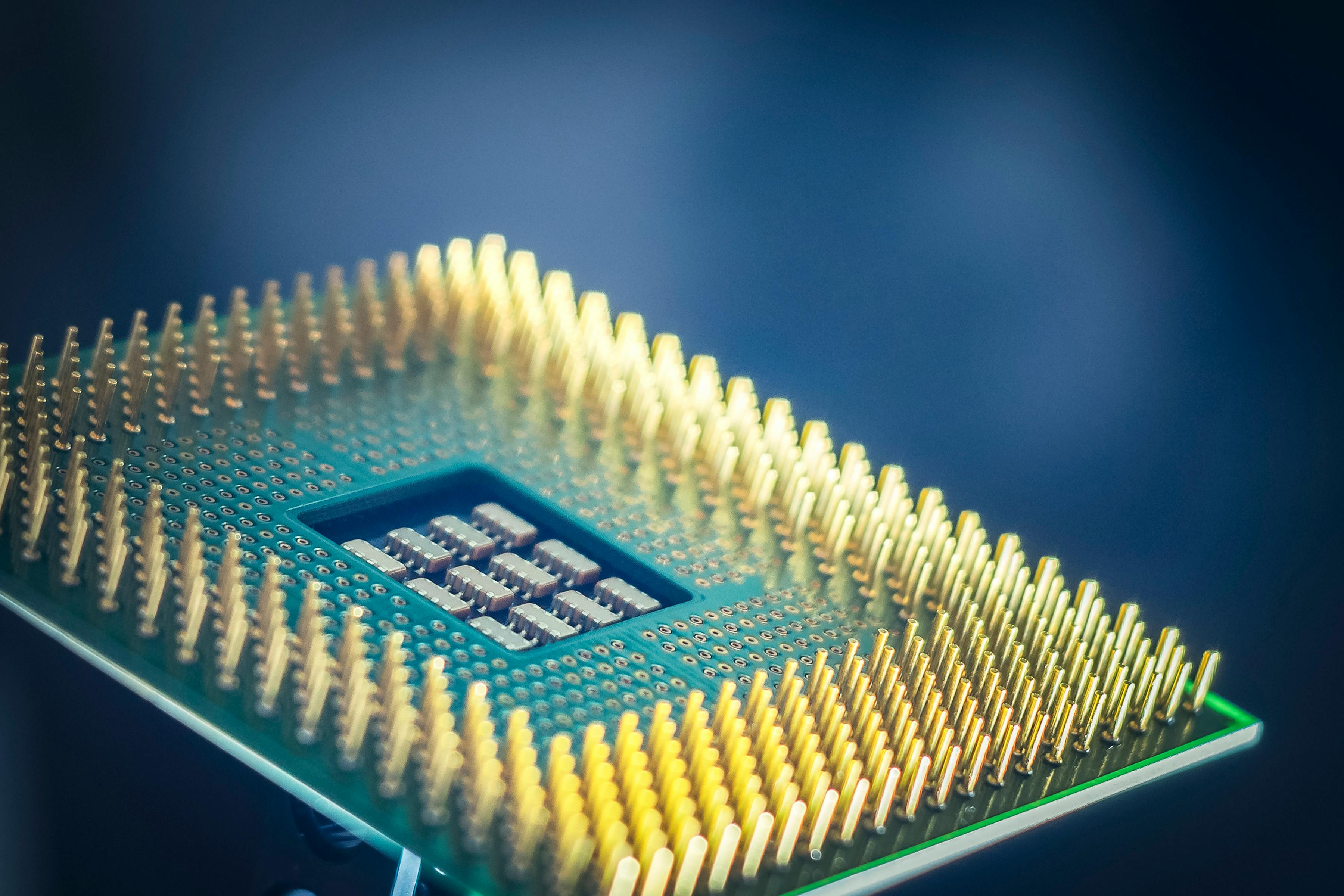 Close-up of a semiconductor wafer with circuitry details under colored lighting