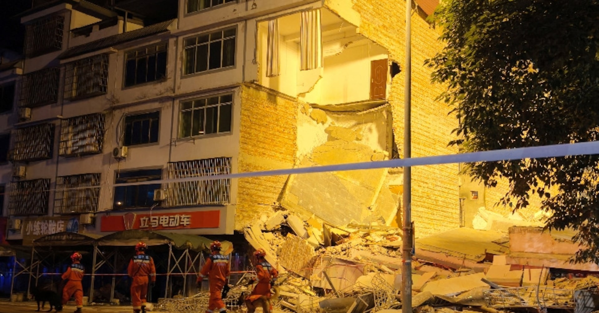Rescue workers walk past a damaged building following an earthquake in Liuzhou