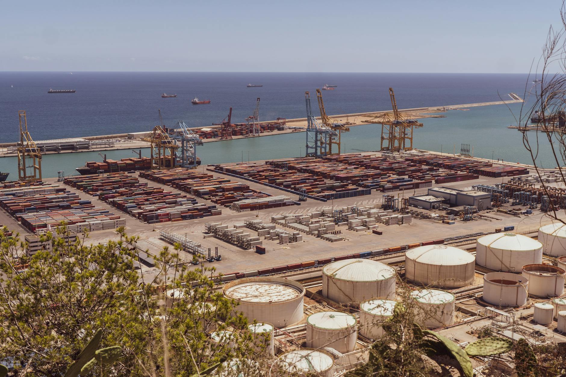 A busy industrial port with cranes and cargo containers alongside the sea.