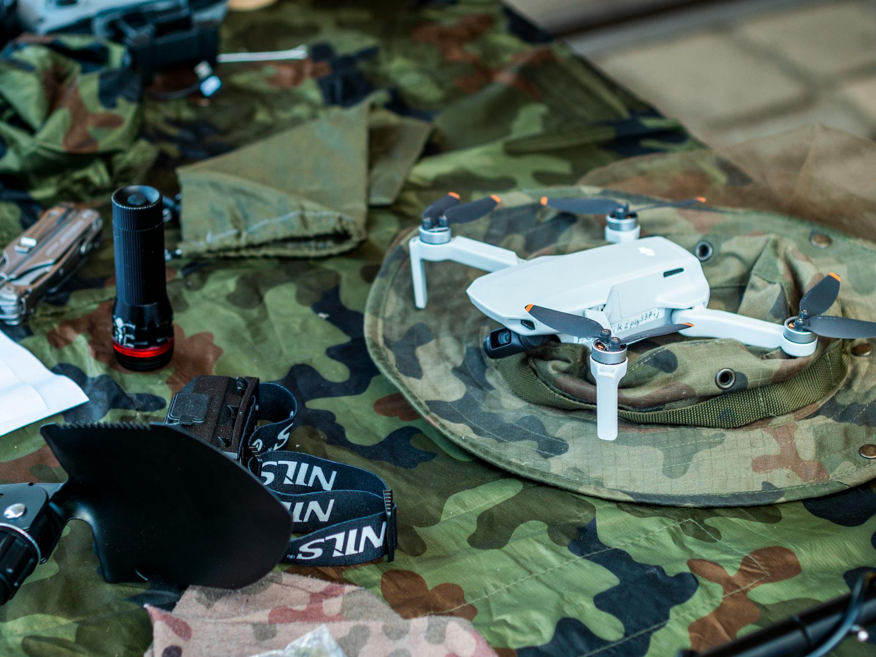 Compact drone resting on camouflage military gear during a training setup