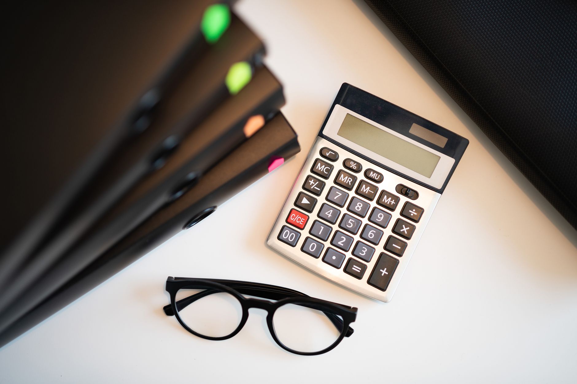Calculator, eyeglasses and loan paperwork on an office desk.