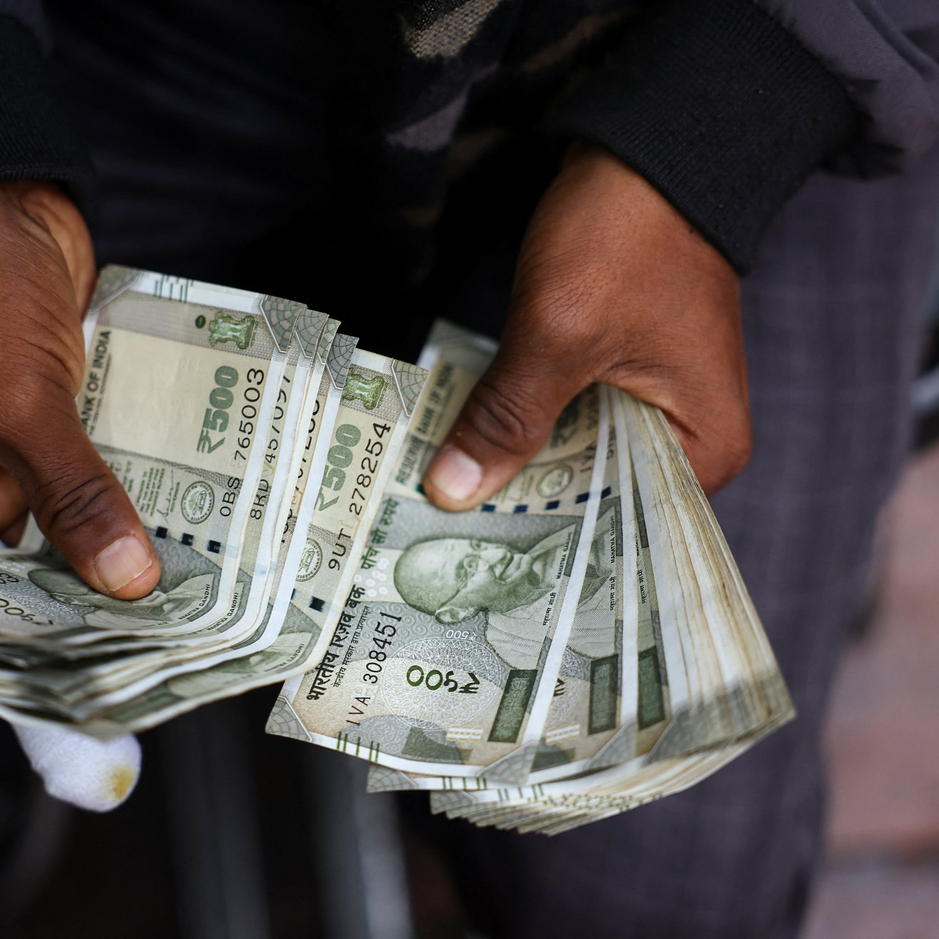 A man counts Indian currency notes at a roadside currency exchange stall in Delhi, India