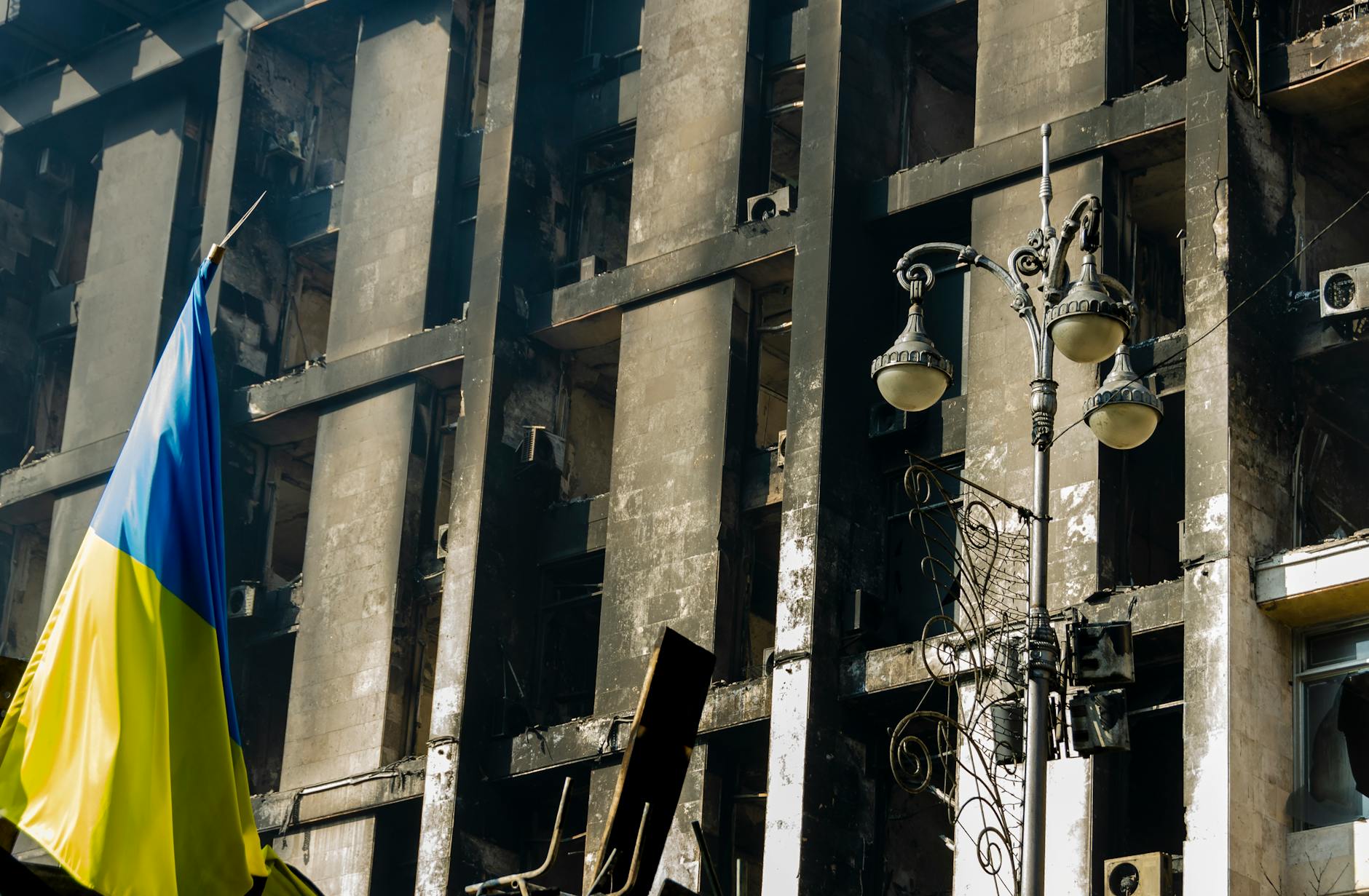 A damaged building in Kyiv, Ukraine with the Ukrainian flag displayed prominently.
