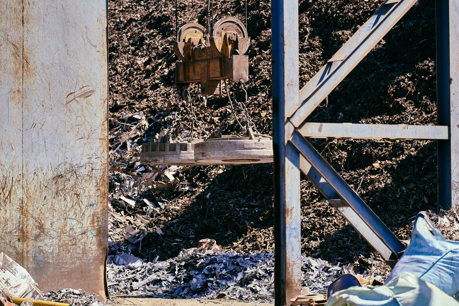 Magnetic crane sorting metal in an industrial scrapyard, reflecting the rare-earth magnet bottleneck facing Pentagon suppliers.