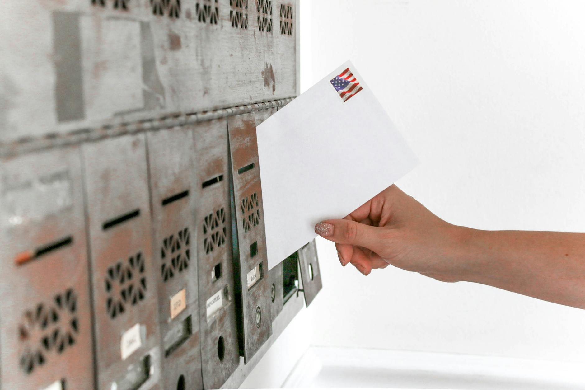 A voter places a stamped envelope into a mailbox, representing mail-in ballots