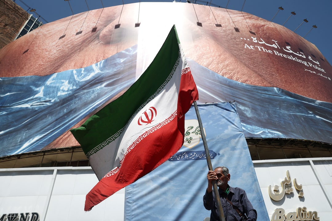 A man holds an Iranian flag near an anti-U.S. billboard in Tehran