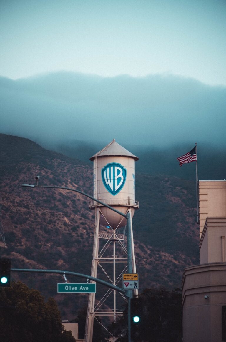 a water tower with a sign on it in front of a mountain